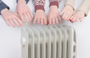 Family warm up hands over electric heater